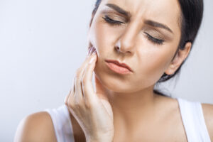 Close-up of a woman experiencing tooth pain due to cold weather sensitivity, highlighting the importance of winter oral health care.