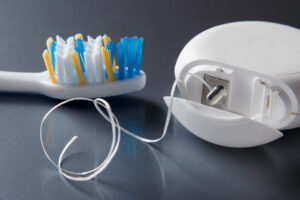 Toothbrush and dental floss on a clean surface to illustrate tools for preventing plaque.